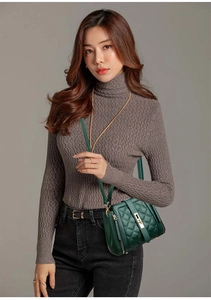Detail of green quilted crossbody bucket bag with gold hardware worn by model