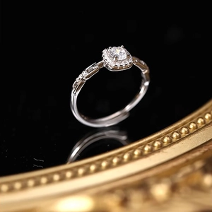 Elegant silver square cut diamond ring with halo pavé crystals on a black reflective surface