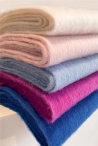 Détail d'écharpes en mohair pliées montrant la texture douce et le dégradé de couleurs