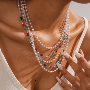 Detail of multilayer baroque necklace featuring white pearls and colorful gemstones