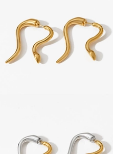 Detail view of gold snake hoop earrings and bicolor heart charms in polished steel