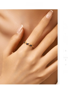 Detail of gold band ring featuring emerald-cut blue stones and small white diamonds