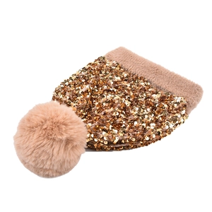 Detailed view of shimmering gold sequins on a thick knitted beanie with a fluffy fur pom-pom