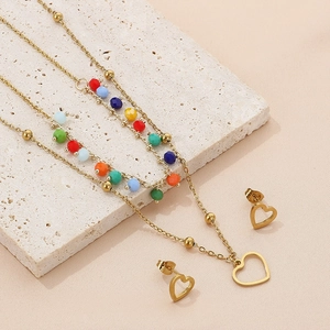 Detailed close-up of a layered gold heart pendant necklace with colorful beads on stone