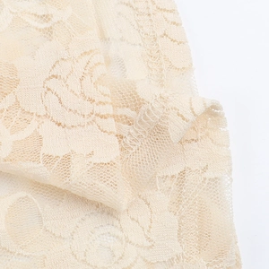 Detailed macro view of the cream lace fabric featuring delicate floral crochet patterns