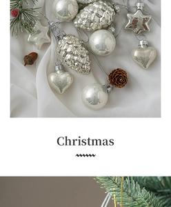 Silver Christmas ornament set with ball, pinecone, and star shapes on white fabric