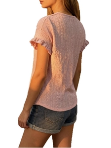 Detail of pink knitted top featuring hollow-out texture and ruffled cuffs with denim shorts