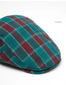 Macro detail of red and green plaid newsboy cap showing woven fabric and foldable brim