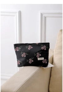 Close-up of vintage black fabric cosmetic bag with pink berry embroidery and brand label