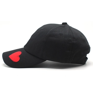 Dettaglio del ricamo a cuore rosso su berretto da baseball nero in cotone lavato e twill