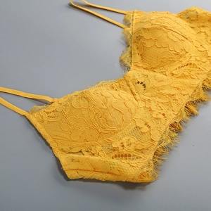 Dettaglio macro del pizzo floreale giallo su un top con spalline sottili e rifiniture