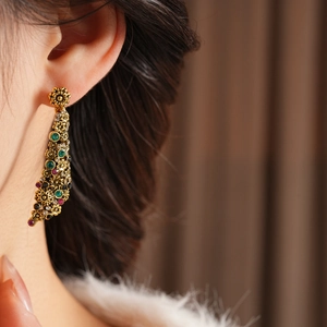 Gros plan de boucles d'oreilles vintage dorées avec cristaux rouges et verts