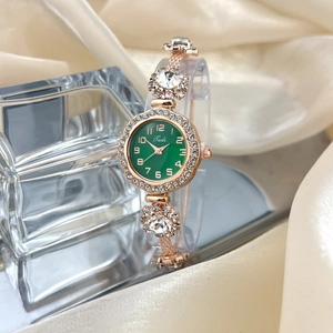 Detail of rose gold watch with green dial and rhinestones on beige silk background