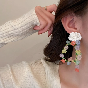 Detail view of colorful acrylic flower earrings worn by a model in a close-up profile shot