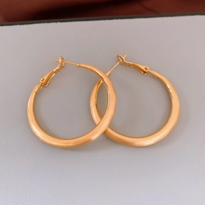 Dettaglio degli orecchini a cerchio placcati oro 18k con finitura in metallo spazzolato