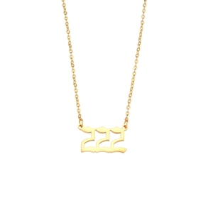 Macro detail of gold stainless steel necklace with gothic 222 number pendant on white background