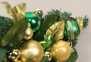 Detailed close-up of green and gold Christmas ornaments with pine needles and golden leaves
