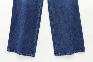Dettaglio delle cuciture a contrasto sull'orlo dei jeans in denim blu indaco
