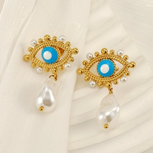 Evil eye pearl earrings with gold accents and baroque pearl drops on silk background