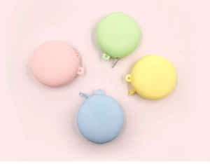 Flat lay of colorful macaron silicone coin purses with zippers on a soft pink background