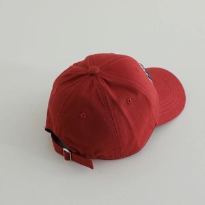 Close-up of the red cotton baseball cap with adjustable metal buckle and strap detail
