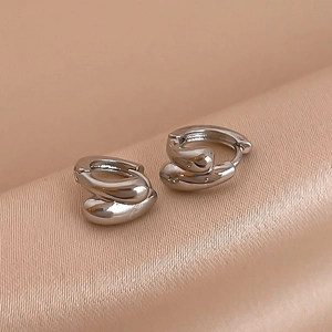 Close-up of silver irregular liquid metal earrings on champagne silk background