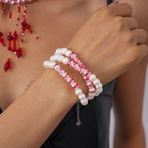 Détail d'un bracelet de perles à trois couches avec accents rouges et chaîne en métal