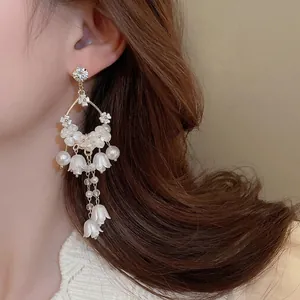 Elegant lily of the valley earrings with pearls and long tassels on a model