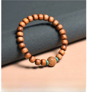 Macro detail of Thuja wood beads with relief carvings and turquoise accents