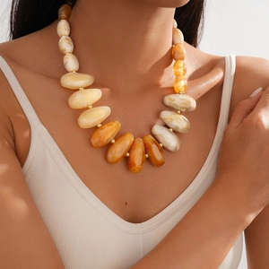 Detail of chunky resin beads with marble texture and golden spacers on the neck