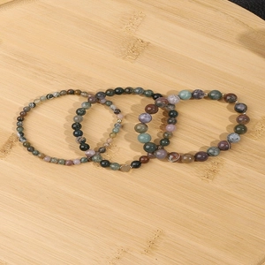 Detail of natural stone bead bracelets with a golden heart pendant on bamboo background