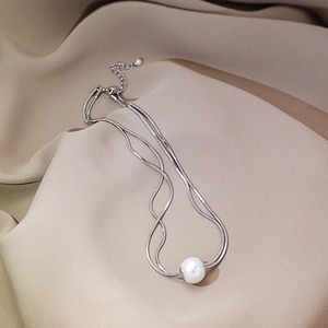 Detailed view of layered silver snake chain necklace featuring a glossy white pearl pendant
