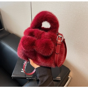 Close-up of red plush faux fur bucket bag with leather strap and silver metal hardware