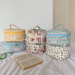 Diverses trousses de maquillage en coton matelassé aux motifs floraux sur un lit doux