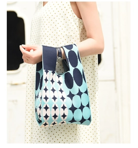 Detail of a geometric knit handbag with navy and light blue patterns in a hand-held view