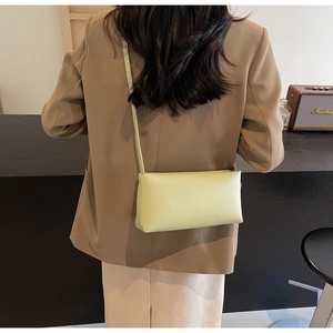 Detail of light yellow leather baguette bag with slender strap on a chic cafe background