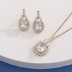 Close-up of gold-plated necklace and earrings set with oval white zircon stones