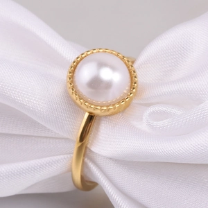 Macro shot of 10MM white pearl ring with golden beaded texture on white silk