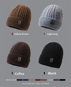Detail of cable knit beanies in yellow brown, light grey, coffee, and black with leather logo