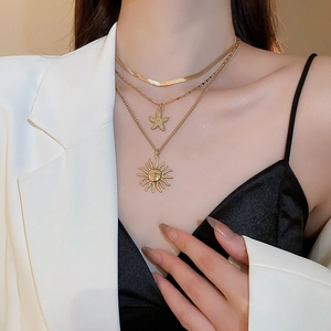 Close-up of triple-layered gold necklaces with starfish and sun pendants on a model