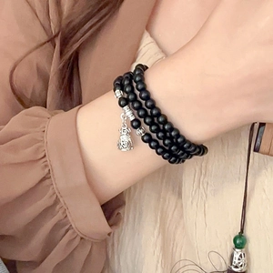 Detail view of multi-layer beaded bracelet with black onyx and silver Fu lucky bag charm