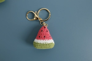 Close-up of handmade crochet watermelon keychain with detailed pink and green knit textures