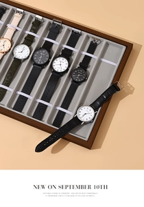 Detail view of quartz watches in multiple colors arranged in a walnut wood display tray