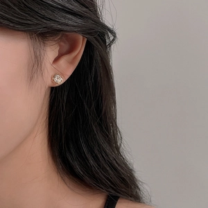 Close-up of model wearing gold hollow rose earring with sparkling zircon stone