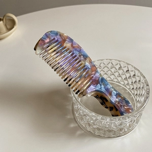 Close-up of portable acetate hair comb with stylish marble and tortoise shell patterns