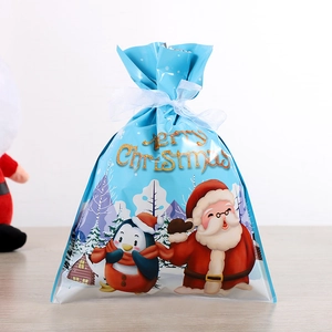 Détail du sac cadeau de Noël avec motifs Père Noël et pingouin et ruban blanc
