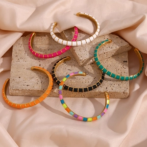 Detailed close-up of colorful enamel and 18K gold plated caterpillar open bangles on silk