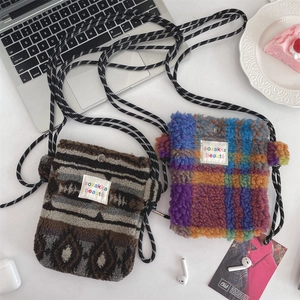 Detail of plush heart crossbody bags in geometric and checkered patterns on a white desk