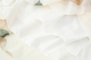Detailed macro view of lightweight floral chiffon fabric with delicate hem stitching