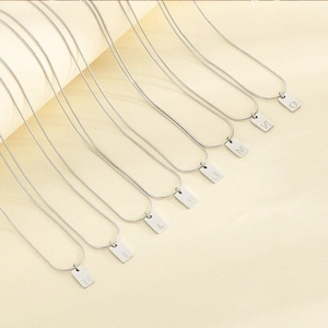 Detailed view of silver initial pendants H to O on snake chains over beige background